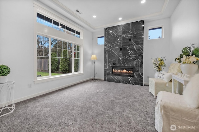 carpeted living area with visible vents, a fireplace, baseboards, and ornamental molding