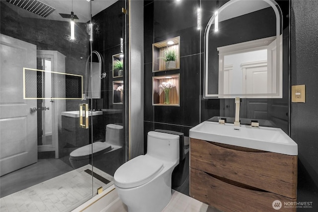 bathroom featuring vanity, a shower stall, toilet, and tile walls