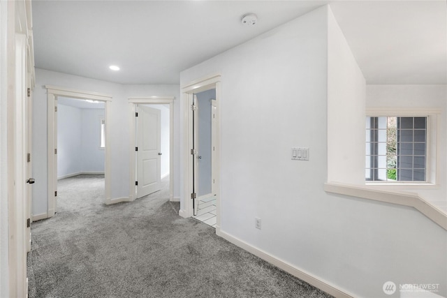 corridor featuring baseboards and carpet