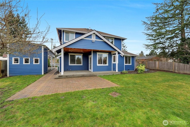 view of front of home with a patio, fence, a front yard, and an outbuilding