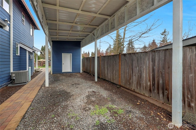 view of patio / terrace with a carport, central air condition unit, and fence