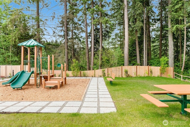 community play area featuring a yard and fence