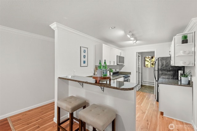 kitchen featuring white cabinetry, open shelves, stainless steel appliances, light wood-style floors, and a kitchen bar