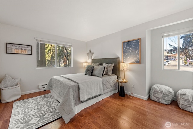 bedroom featuring a baseboard radiator, baseboards, and wood finished floors