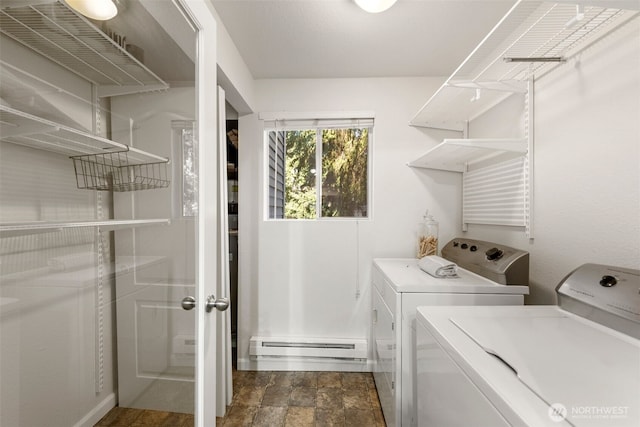 clothes washing area featuring baseboard heating, washing machine and dryer, laundry area, and stone finish floor