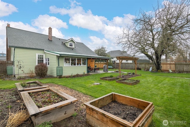 back of property with a lawn, a chimney, a fenced backyard, a garden, and a patio