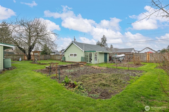 back of property featuring a lawn, a vegetable garden, and a fenced backyard