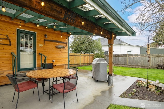 view of patio with grilling area, outdoor dining area, and fence