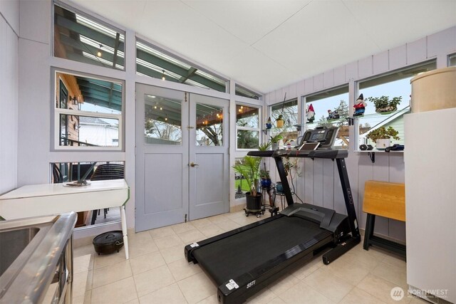 workout room featuring lofted ceiling and tile patterned flooring