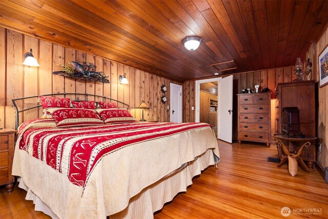 bedroom with attic access, wood ceiling, wooden walls, and wood finished floors