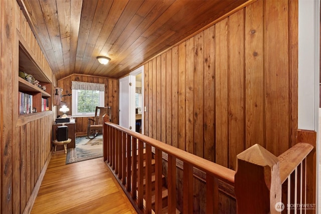 hall featuring wood walls, wooden ceiling, lofted ceiling, and wood finished floors