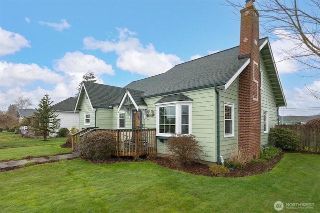 view of front facade featuring a front lawn, fence, roof with shingles, and a chimney