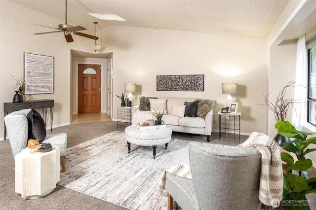 carpeted living area with lofted ceiling with skylight, a ceiling fan, baseboards, and a textured ceiling