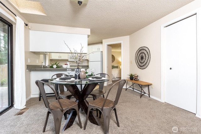 dining space featuring visible vents, baseboards, light colored carpet, and a textured ceiling