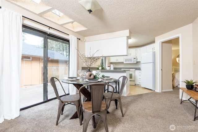 dining room featuring light colored carpet, a skylight, and a textured ceiling