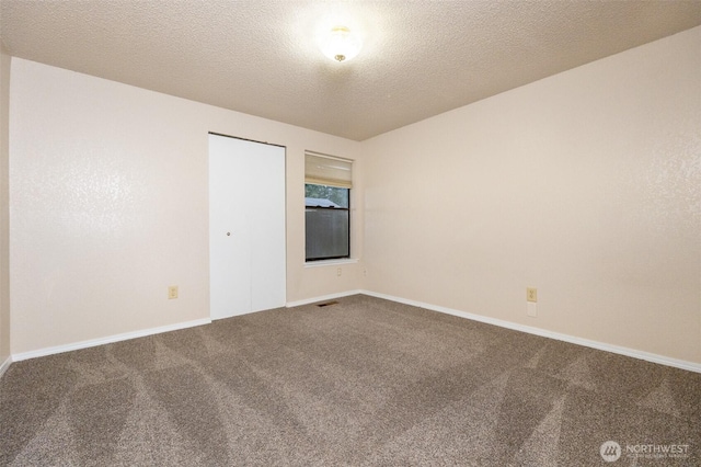 carpeted empty room featuring visible vents, a textured ceiling, and baseboards