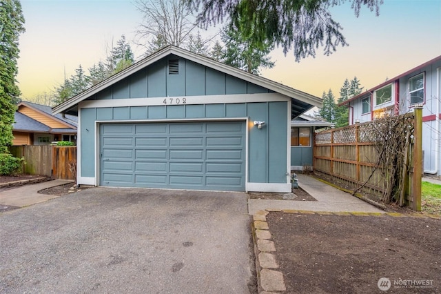 garage at dusk featuring fence