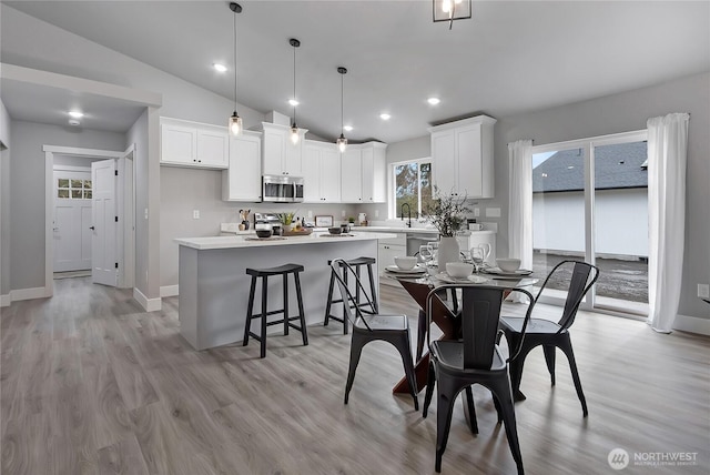 dining space with recessed lighting, light wood-style flooring, baseboards, and lofted ceiling