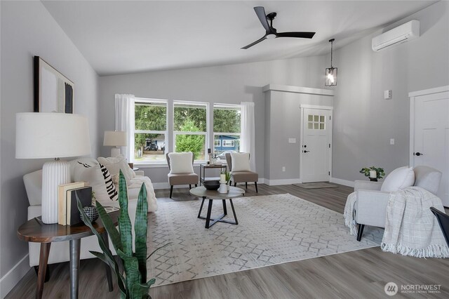 living room featuring baseboards, ceiling fan, a wall mounted air conditioner, lofted ceiling, and wood finished floors