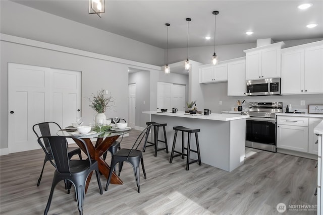 kitchen featuring a center island, white cabinets, a kitchen breakfast bar, and stainless steel appliances