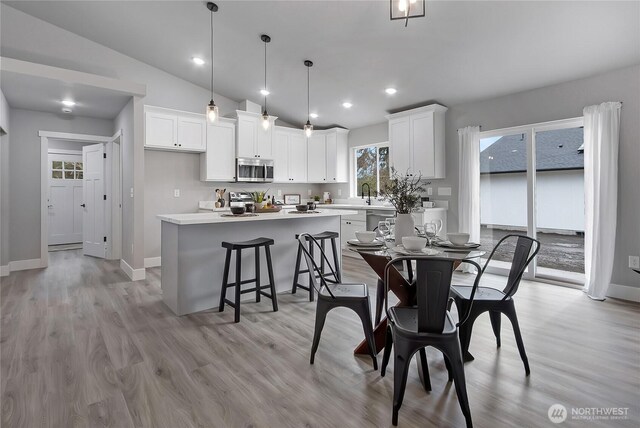 dining space with lofted ceiling, recessed lighting, light wood-style floors, and baseboards