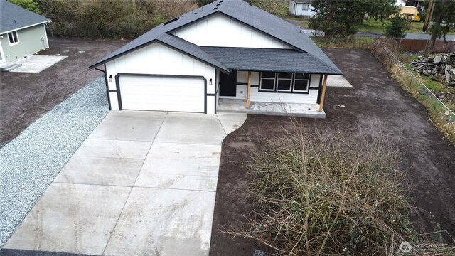 ranch-style house featuring a garage, board and batten siding, driveway, and a shingled roof