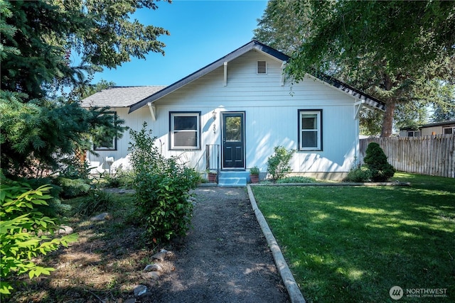 bungalow-style home featuring a front lawn and fence