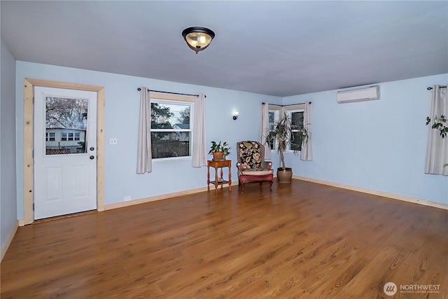 living area with wood finished floors, baseboards, and a wall mounted air conditioner