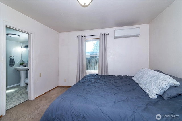 carpeted bedroom featuring connected bathroom, baseboards, and a wall unit AC