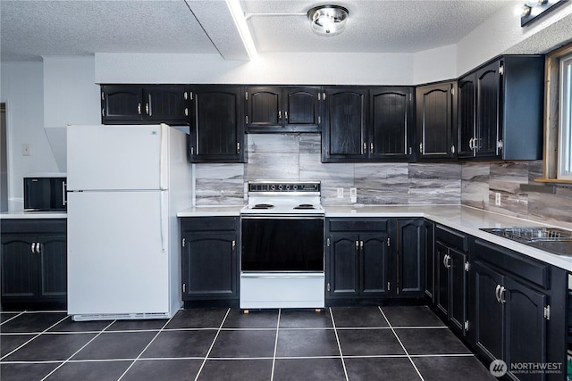 kitchen with light countertops, dark cabinetry, freestanding refrigerator, electric stove, and dark tile patterned flooring