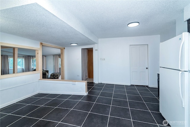 interior space with baseboards, dark tile patterned flooring, and a textured ceiling