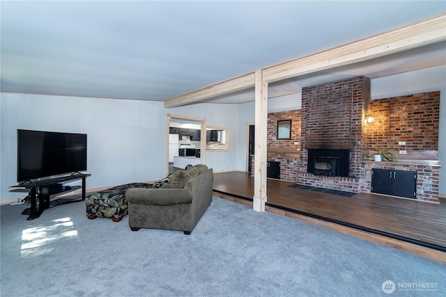 carpeted living room featuring beamed ceiling and a fireplace