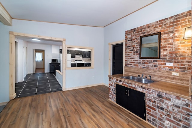 kitchen featuring electric range, a sink, dark cabinetry, dark wood finished floors, and crown molding