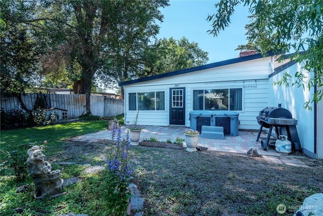 back of property with a chimney, a patio area, a lawn, and fence private yard