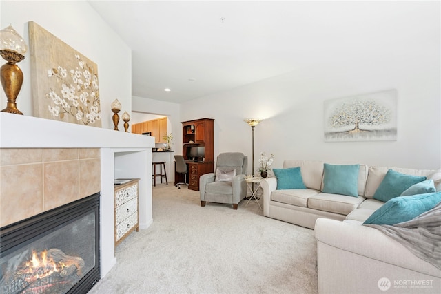 living area featuring a tiled fireplace and light colored carpet