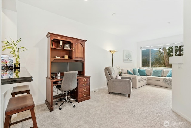 office area featuring baseboards and light carpet