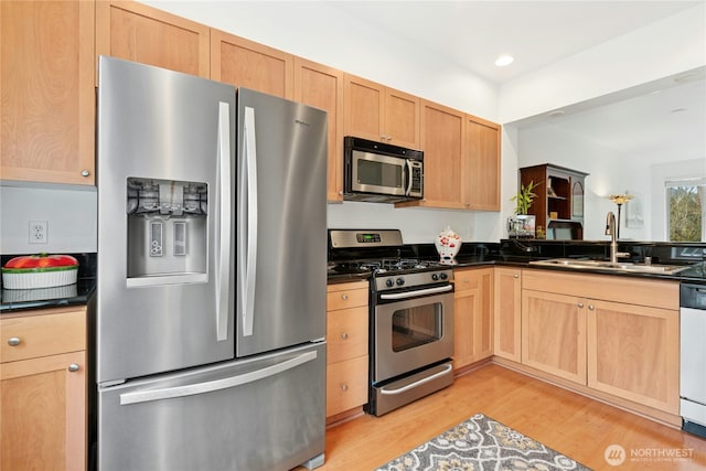 kitchen with a sink, dark countertops, recessed lighting, stainless steel appliances, and light wood-style floors