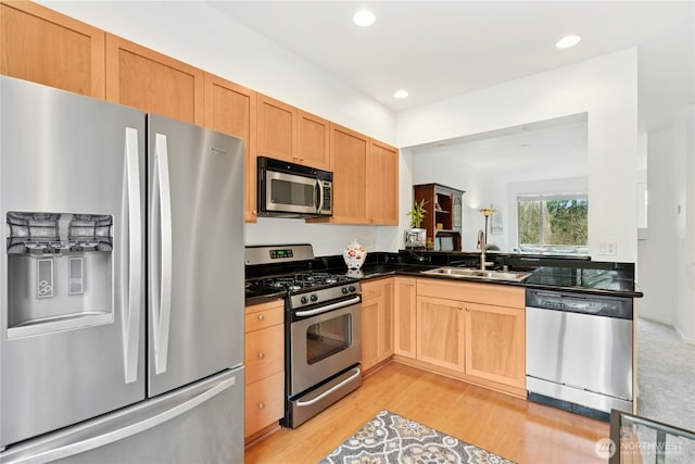 kitchen with a sink, dark countertops, recessed lighting, light wood-style floors, and appliances with stainless steel finishes