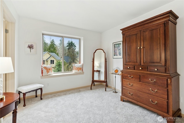 sitting room with baseboards and light carpet