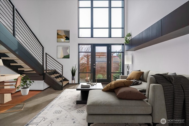 living room with stairway, a towering ceiling, and french doors