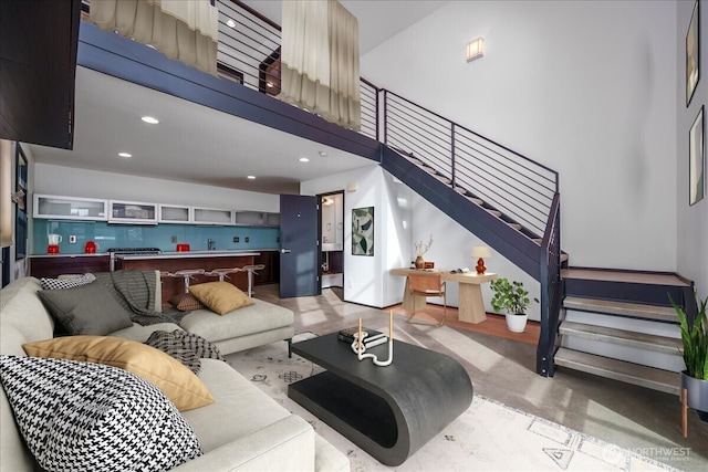 living area featuring stairway, recessed lighting, and a high ceiling