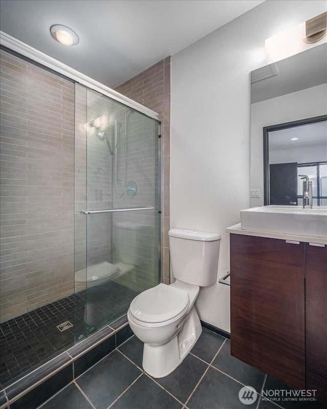 full bathroom featuring vanity, baseboards, a stall shower, tile patterned flooring, and toilet