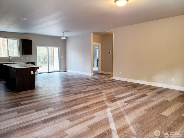 interior space featuring baseboards, light wood-style floors, and a sink