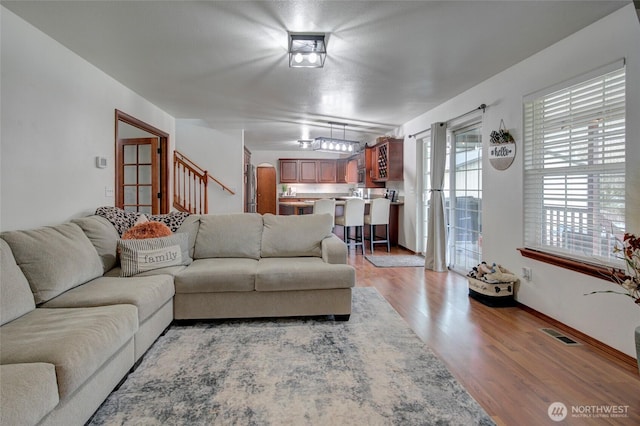 living room featuring visible vents, stairs, and light wood-style floors