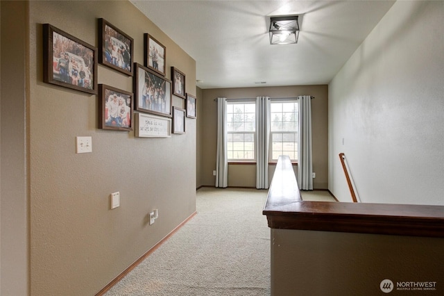 corridor featuring an upstairs landing, light colored carpet, and baseboards