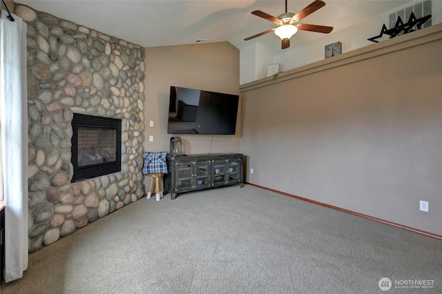 unfurnished living room featuring a stone fireplace, vaulted ceiling, carpet floors, and ceiling fan