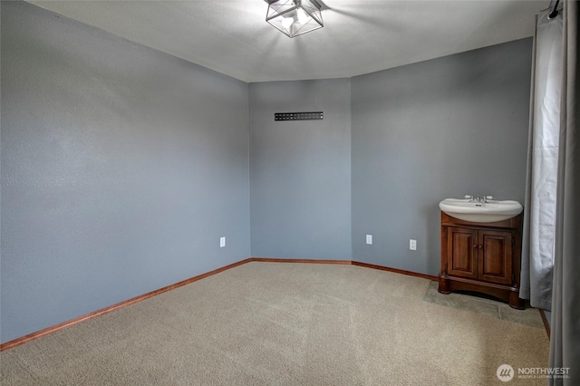 unfurnished room with carpet flooring, baseboards, and a sink