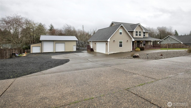 view of property exterior featuring an outbuilding, a porch, a detached garage, and fence