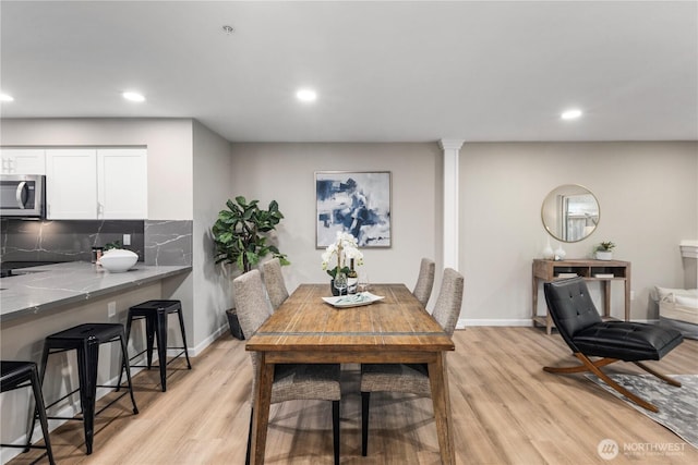 dining space featuring recessed lighting, light wood-type flooring, and ornate columns