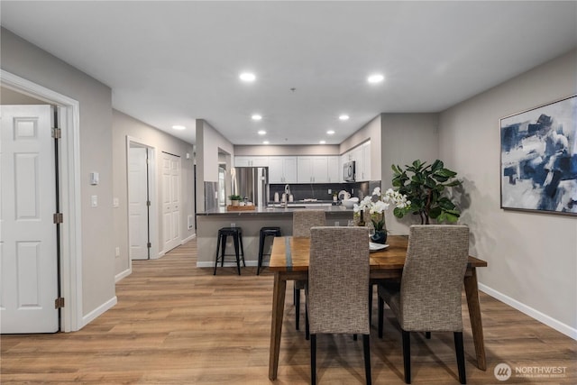 dining room featuring recessed lighting, baseboards, and light wood finished floors